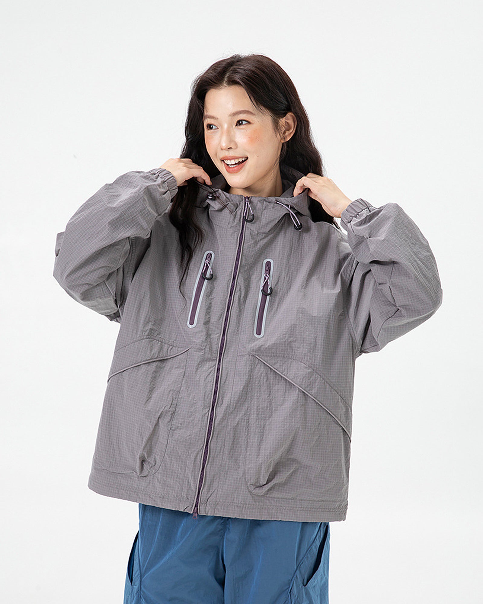 Woman wearing Rose Ash hooded softshell windbreaker jacket adjusting collar, studio