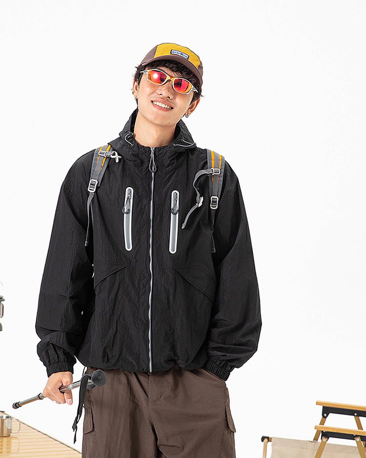 Man wearing Obsidian Black hooded softshell windbreaker jacket, outdoor camping lifestyle scene