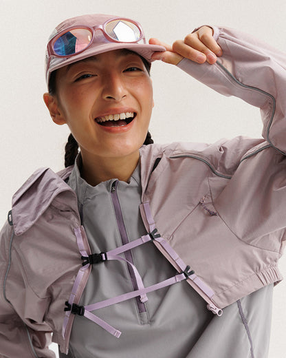 Grapefruit Pink 2-in-1 detachable jacket layered open over grey inner half-zip on smiling female model, chest webbing buckles, lifestyle techwear