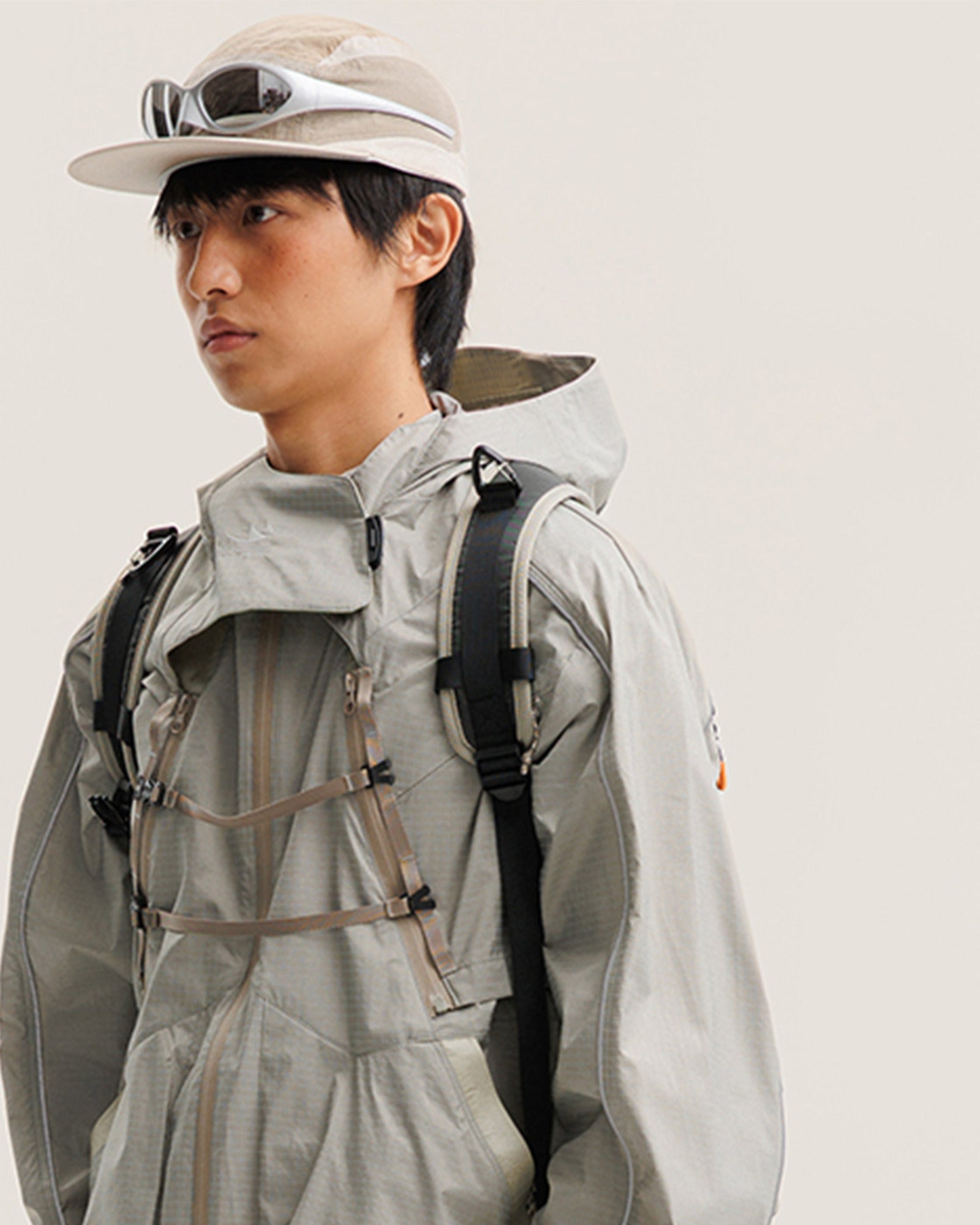 Sandstone Khaki 2-in-1 detachable hooded jacket combined form on male model with backpack, chest webbing buckles, outdoor techwear half body