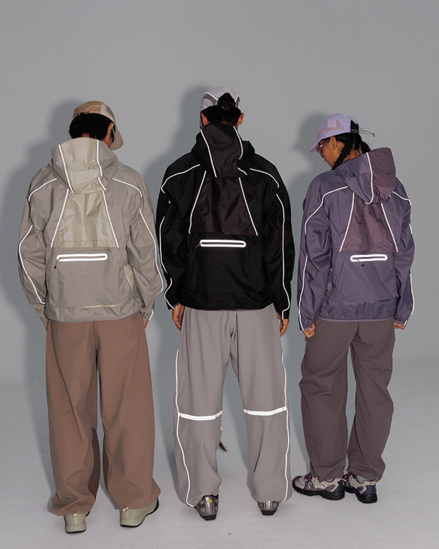 Back view of three models in the 2-in-1 detachable jacket showing reflective piping and back reflective zip pockets glowing, night-ride techwear