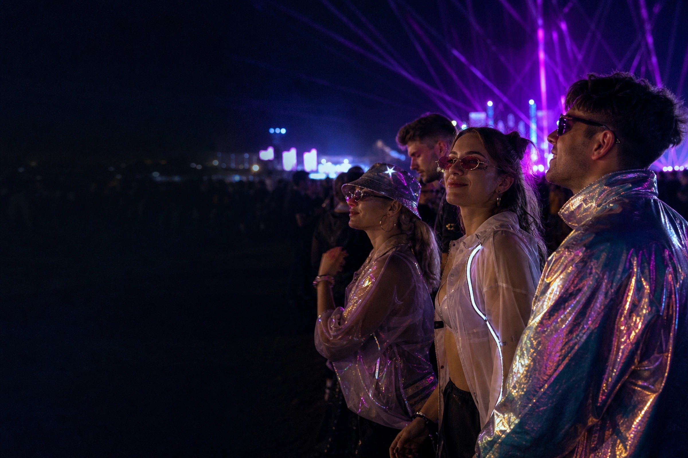 Festivalgoers in generic reflective outfits at an outdoor techno rave at night
